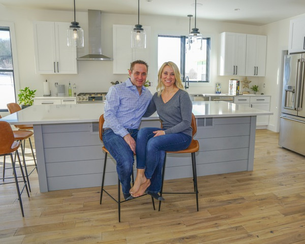 smiling couple sits on kitchen stools