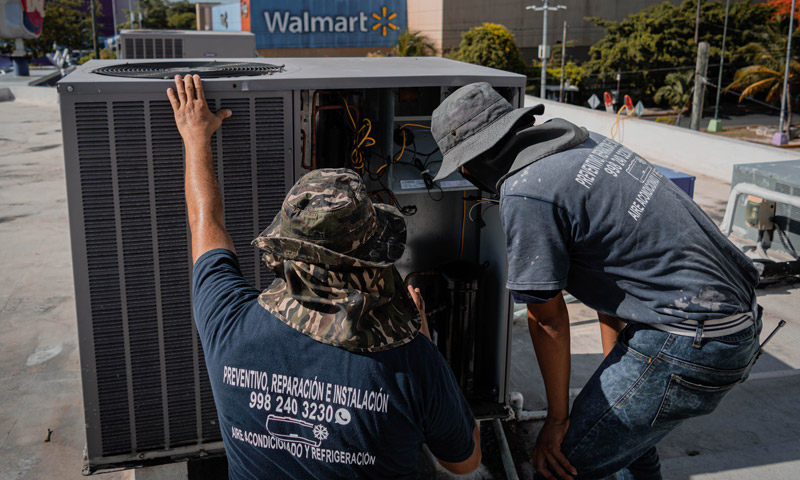 two HVAC technicians inspecting an air conditioning unit